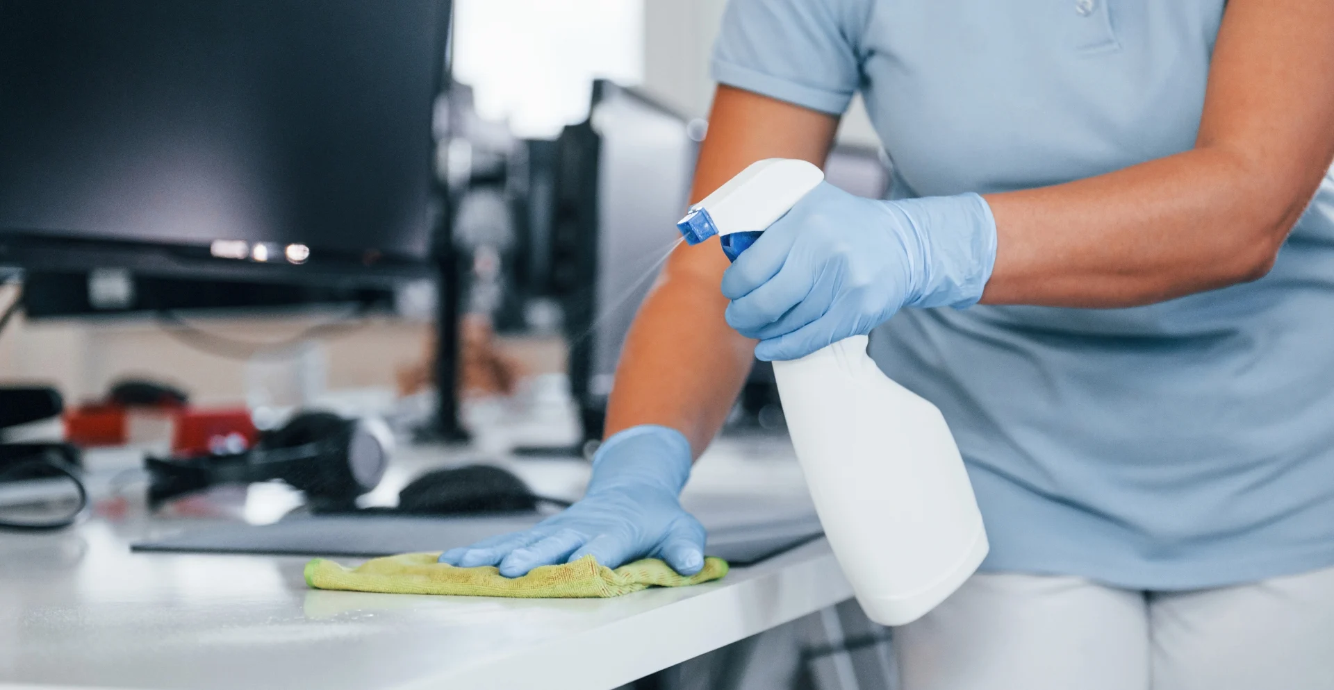 Sanitizing team spraying disinfectant on office high-touch surfaces